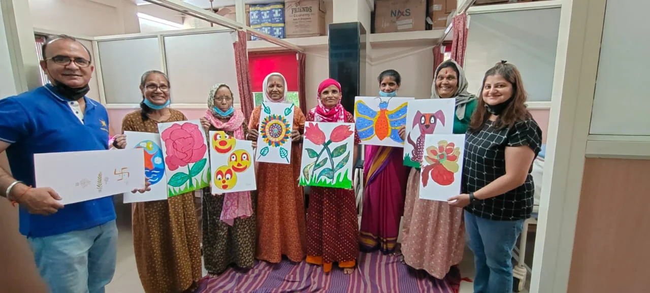 Elderly woman smiling, wrapped in an orange saree with a headscarf — a beneficiary of the Live Life Love Life Charity Foundation's cancer care programs
